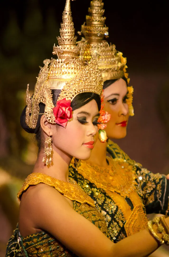 Two women in gold and red outfits are standing.