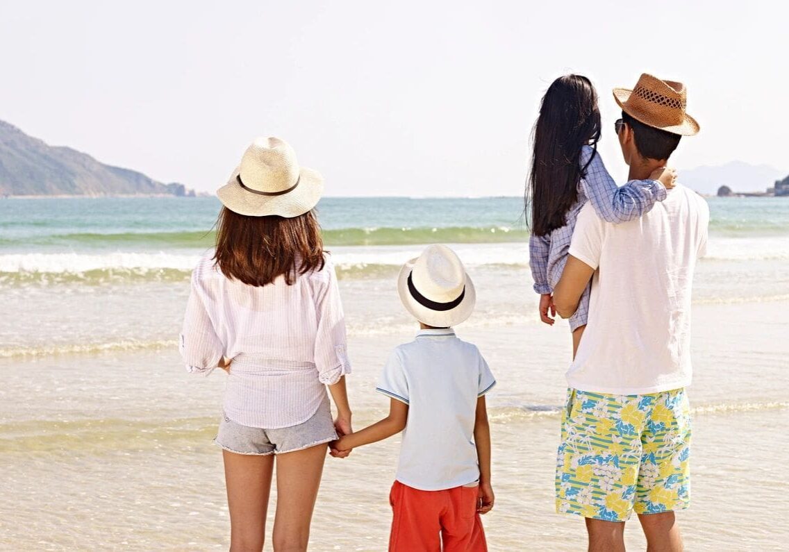 A family standing on the beach holding hands.